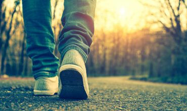 A person walking on the road with their shoes off