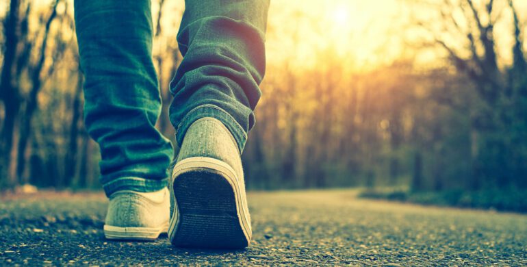 A person walking on the road with their shoes off