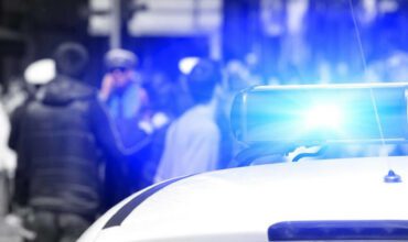 A police car with lights on and people in the background.